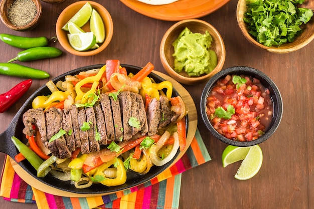 Steak fajitas met paprika en gele ui op een gietijzeren fajita koekenpan.