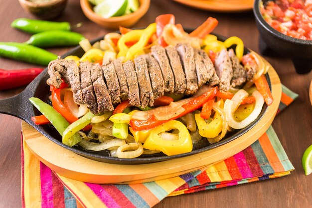 Steak fajitas with bell peppers and yellow onion on a cast iron fajita skillet.