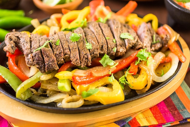 Steak fajitas with bell peppers and yellow onion on a cast iron fajita skillet.