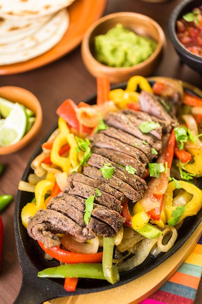 Steak fajitas with bell peppers and yellow onion on a cast iron fajita skillet.