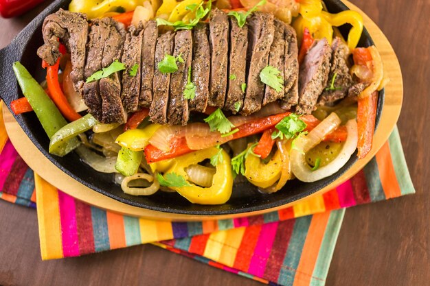 Steak fajitas with bell peppers and yellow onion on a cast iron fajita skillet.