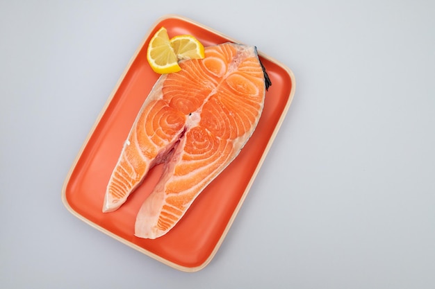 Стейк рыбы лосося с лимоном на оранжевом маленьком блюде