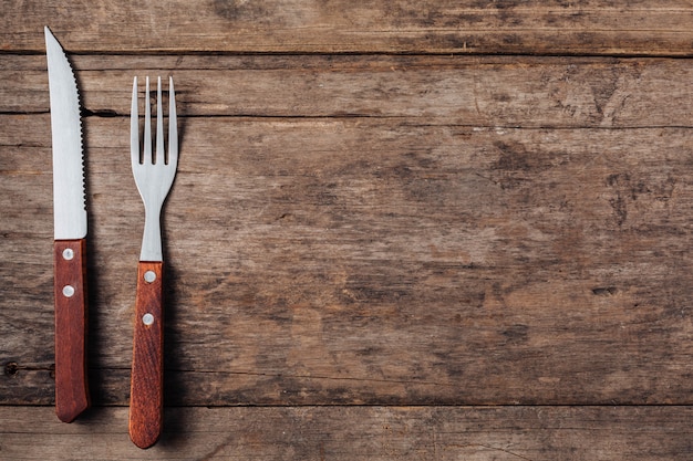 Steak fork and knife on wooden background