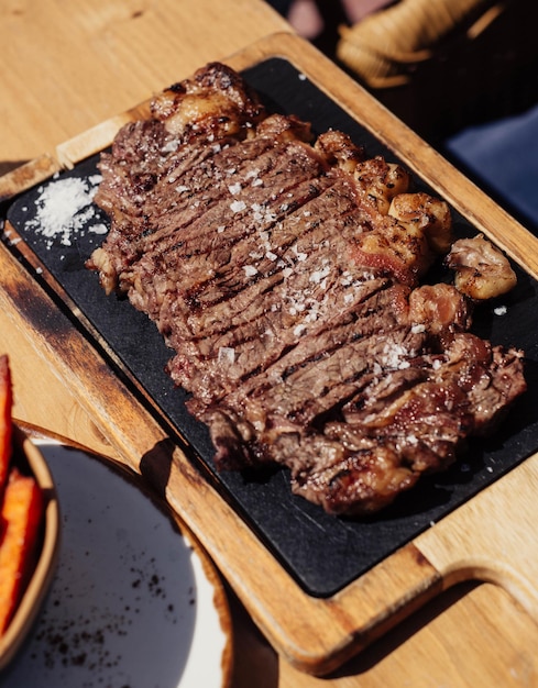 A steak on a grill with carrots and fries