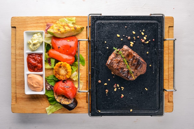 Steak and grilled vegetables on the board Top view Free space for text On a wooden background