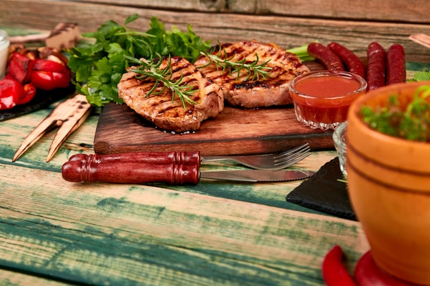 Steak pork grill on wooden cutting board with a variety of grilled vegetables