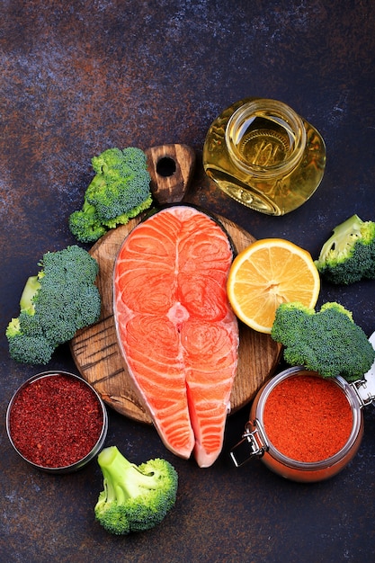 Steak of raw salmon with lemon and olive oil on a dark background Top view.