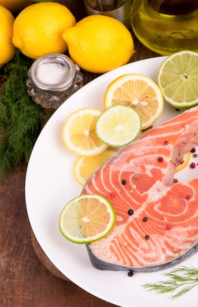 Steak of red fish and sliced lemons on wooden table