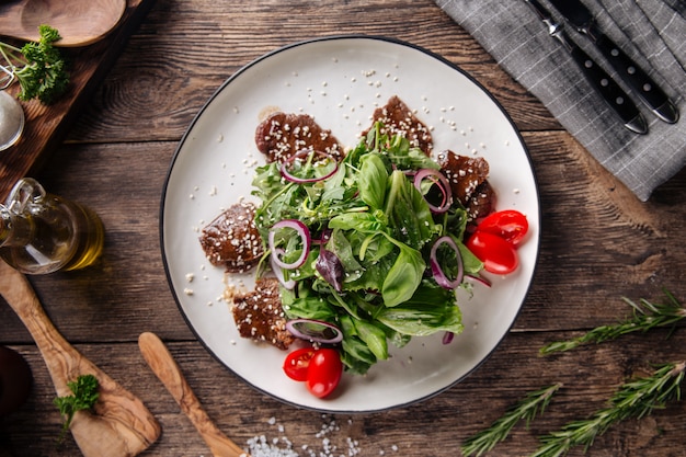 Steak salad with greens tomato and red onion