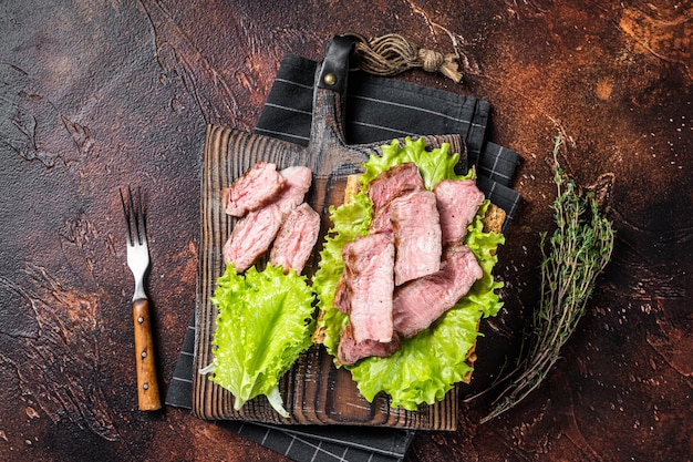 Steak sandwich with sliced roast beef salad and vegetables Dark background Top view