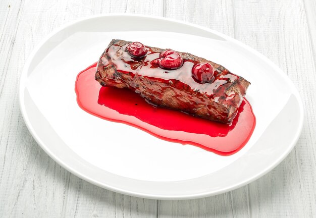 Steak with cherry sauce on a white plate