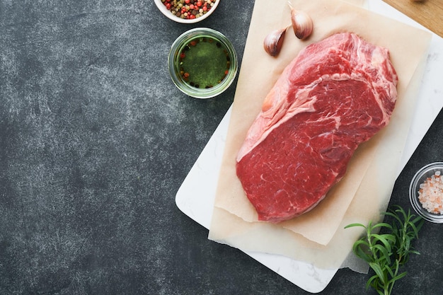 Steaks Fresh New York Steaks raw with spices rosemary and pepper on black marble board on gray background Top view Mock up