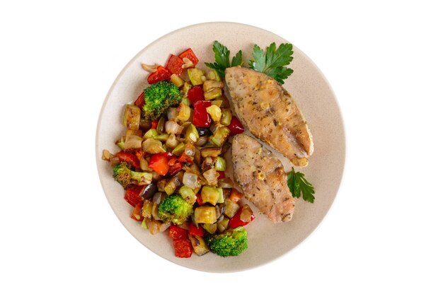 Steaks of fried spicy fish, served with a warm vegetable salad on a plate