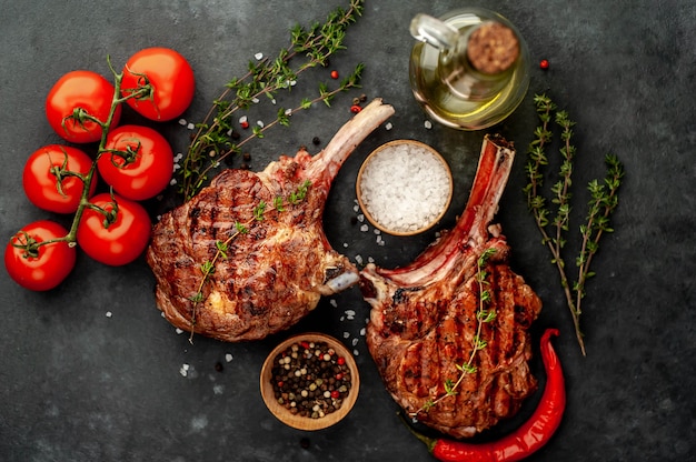 steaks - gegrilde rundvlees tomahawks met kruiden, tijm op een stenen achtergrond. met kopie ruimte voor uw tekst