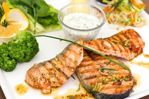 Photo steaks of salmon, grilled. served with vegetables and spices on a white plate