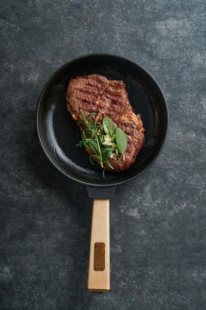 ステーキ スライスした焼き肉のステーキ ニューヨークまたはリブアイ スパイス ローズマリーとコショウを鉄鍋に黒い古い木製の背景の大理石の板にトップ ビュー モックアップ