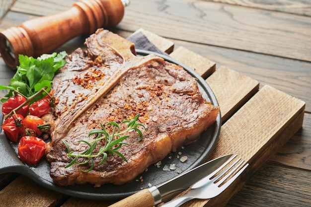 Steaks Tbone Gesneden rundvlees gegrilde Tbone of porterhouse vlees steak met kruiden rozemarijn en peper op zwart marmeren bord op oude houten achtergrond Bovenaanzicht Mock up