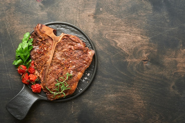 Photo steaks tbone sliced beef grilled tbone or porterhouse meat steak with spices rosemary and pepper on black marble board on old wooden background top view mock up