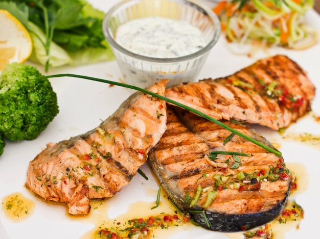 Steaks van zalm, gegrild. Geserveerd met groenten en kruiden op een witte plaat