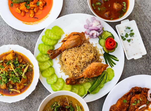 Steam chicken biryani pulao rice makhni chicken boneless handi haleem chicken karahi korma nihari tandoori salad and raita served isolated on background top view of indian and pakistani food