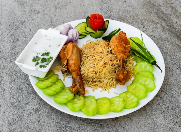 Steam chicken leg piece biryani pulao rice with salad and raita served in dish isolated on background top view of indian spices and pakistani food