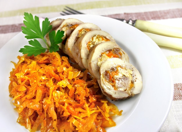 Steam chicken roll with carrot, cheese and nuts served on a plate with spicy stewed cabbage