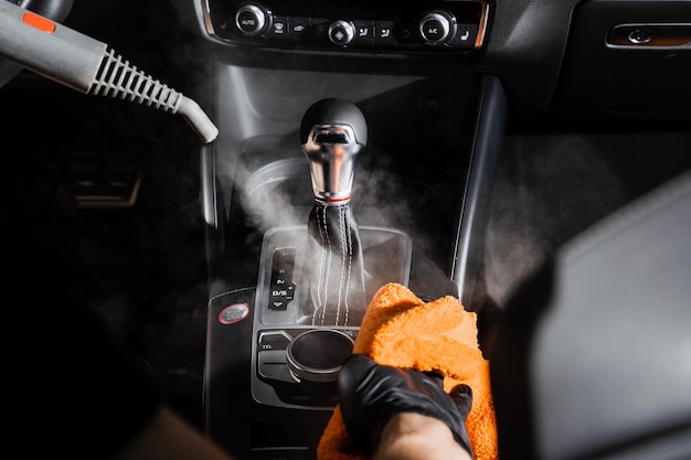 Steam cleaning of gearbox and dashboard in car Vaping steam Cleaning individual elements of black leather interior in auto Creative advert for auto detailing service