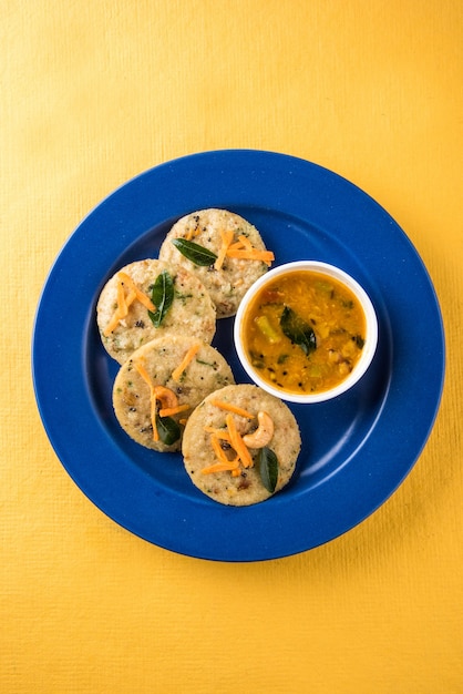 Foto torte di semola cotte a vapore conosciute come rava idli o pigramente. servito con sambar e chutney di cocco. messa a fuoco selettiva