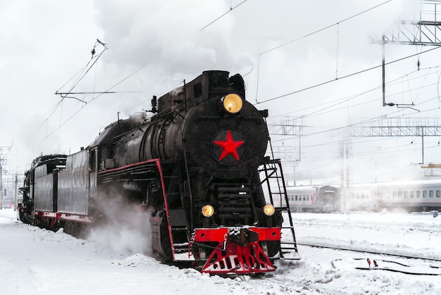 Steam locomotive arrives at the railway junction in winter