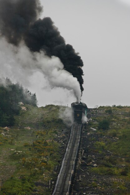 Foto treno a vapore della mount washington cog railway che spinge l'allenatore alla vetta in buone condizioni meteorologiche