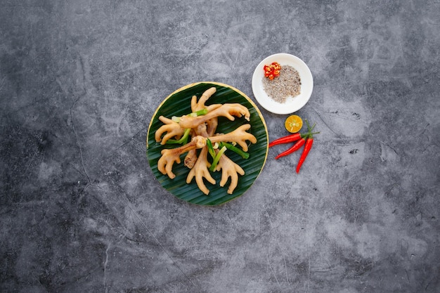 Куриные ножки на пару с зеленым луком, чесноком и рыбным соусом подаются в миске, изолированной на темно-сером фоне, вид сверху на японскую еду