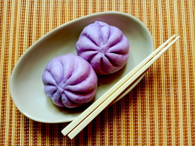 Steamed Chinese Bun with taro filling on a bowl with chopsticks