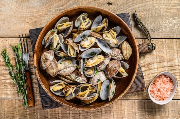 Steamed cooked shells Clams vongole in a wooden plate. wooden background. Top view.