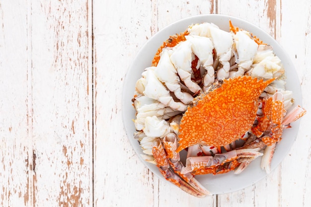 steamed crabs in white ceramic plate on white old wood texture background with copy space for text top view flat lay blue swimming crab flower crab blue crab