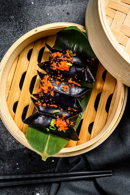 Steamed dumplings Dim Sum in bamboo steamer.  Black background. Top view