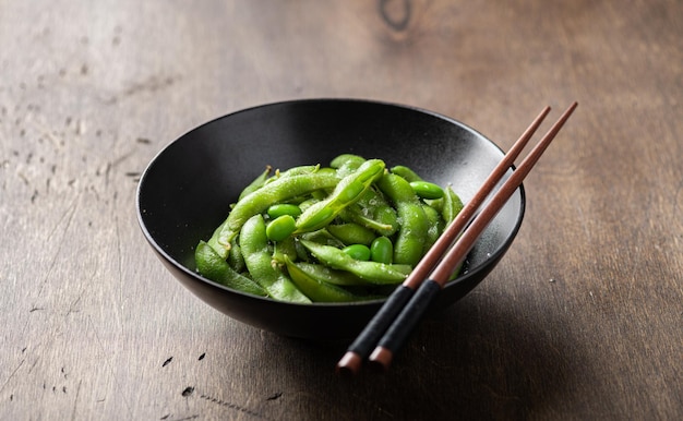 Steamed edamame beans in a black ceramic bowl soybeans selective focus