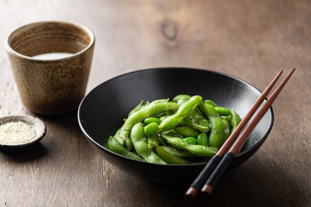 Steamed edamame beans in a black ceramic bowl soybeans selective focus