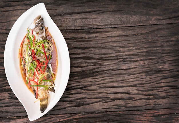 나무 테이블에 흰 접시에 간장 찐된 생선.