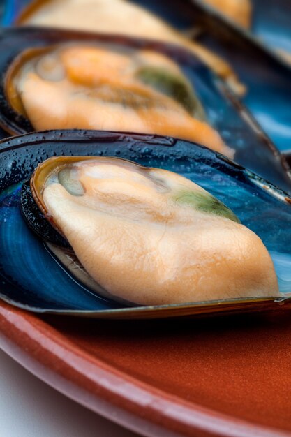 Steamed mussels close-up. With shell on clay plate.