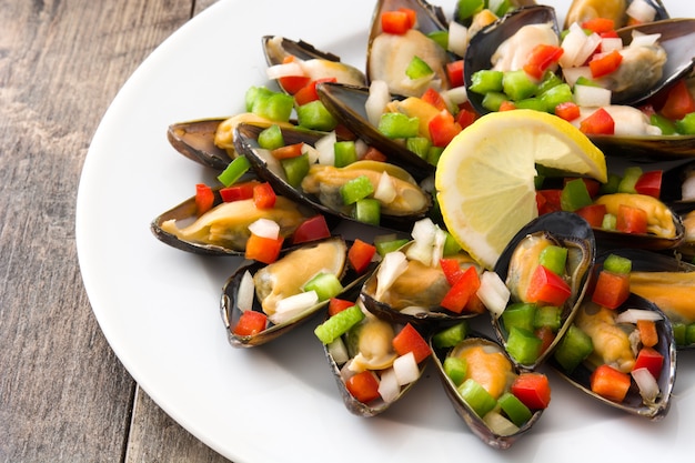 Steamed mussels with peppers and onion on wooden table