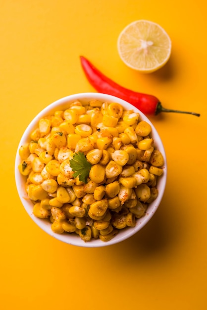 Steamed organic yellow sweet corn masala or corn chat prepared using butter, chat masala and lemon, favourite indian snack