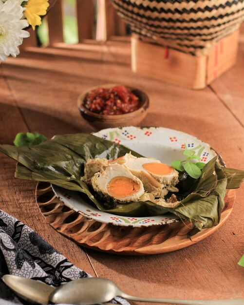 Steamed Salted Egg (Pepes Telur Asin) Wrapped with Banana Leaf and Garnish with Lemon Basil