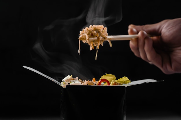 Steaming hot rice in wok box on black surface