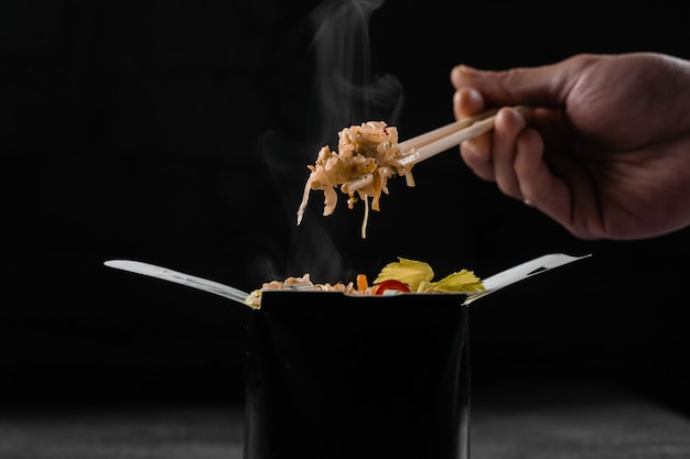 Steaming hot rice in wok box on black surface