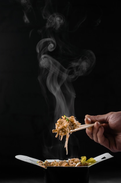 Steaming hot rice in wok box on black surface