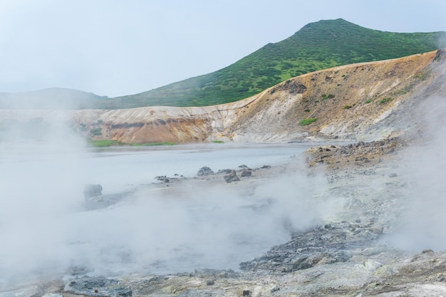 Steaming hydrothermal outlet on the shore of the hot lake in the caldera of the Golovnin volcano on the island of Kunashir