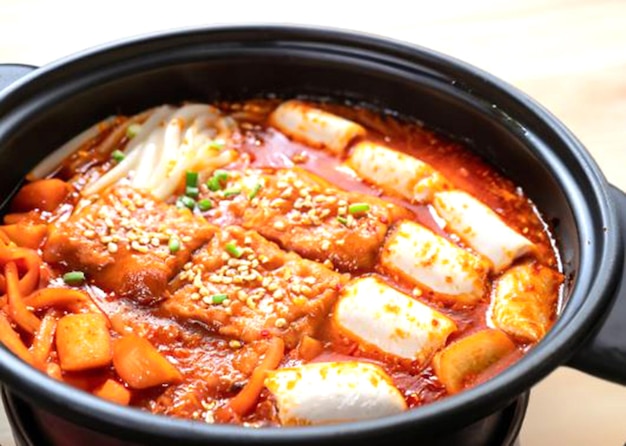 a steaming pot of tteokbokki spicy rice cakes simmering in a rich gochujangbased sauce