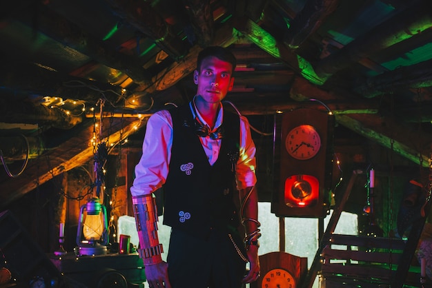 Steampunk cosplay. A male inventor in a suit with gears in a workshop with a neon light