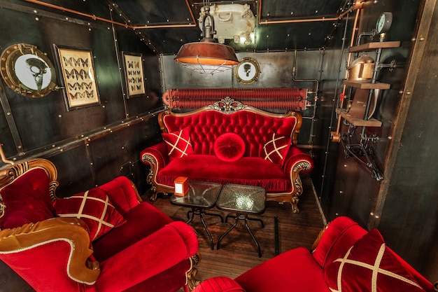 Steampunk-stijl donker interieur met rood fluwelen fauteuils en een bank met kussens