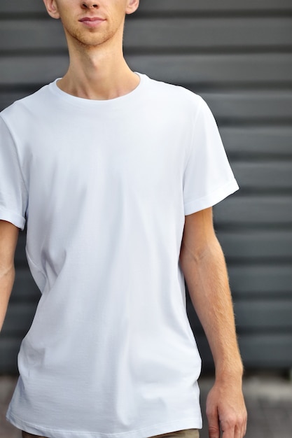 Stedelijk model van kleding. Jonge man gaat in de buurt van de grijze metalen geprofileerde muur in een leeg T-shirt, ondiep van de DOF. Sjabloon klaar voor u ontwerp.